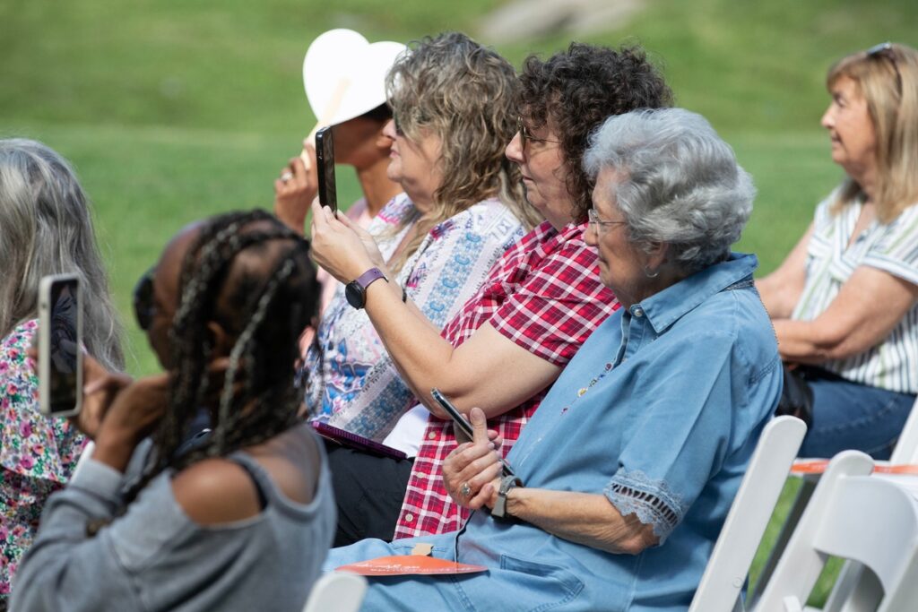 Audience members record Heidi Ratliff-Walker’s remarks Friday as she describes surviving Stage 4 metastatic cervical cancer through treatment received at HCA Florida North Florida Hospital