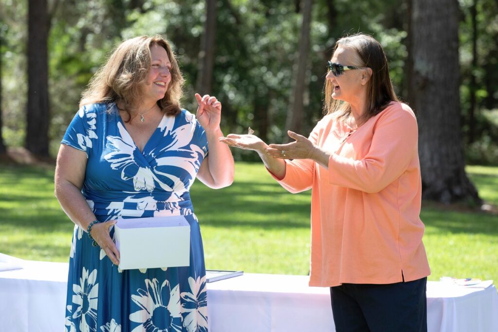 Fellow cancer survivor Denise Pearce, right, holds a butterfly aloft while speaking to keynote speaker Heidi Ratliff-Walker Friday during HCA Florida North Florida Hospital’s annual butterfly release ceremony. During the event, attendees released about 100 farm-raised painted lady butterflies in honor of cancer survivors.