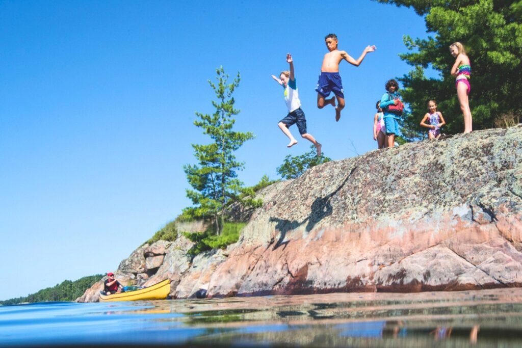 Kids swimming and jumping into a lake. Metro Creative