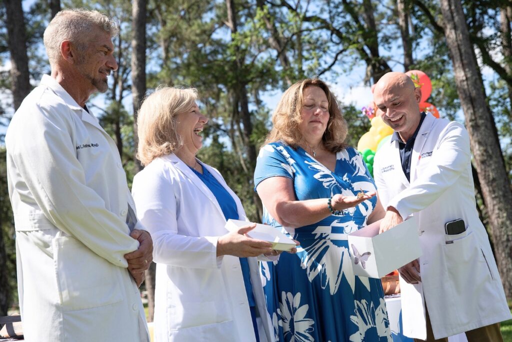 Radiation oncologist Dr. Charles “Trey” Perkins III, from left, gynecologic oncologist Dr. Daylene Ripley, keynote speaker Heidi Ratliff-Walker and HCA Florida North Florida Hospital Chief Medical Officer Dr. Alex Gumiroff encourage painted lady butterflies to leave their box Friday during the Gainesville hospital’s annual butterfly release ceremony. Perkins and Ripley are part of the HCA medical team that successfully treated Ratliff-Walker for Stage 4 metastatic cervical cancer.
