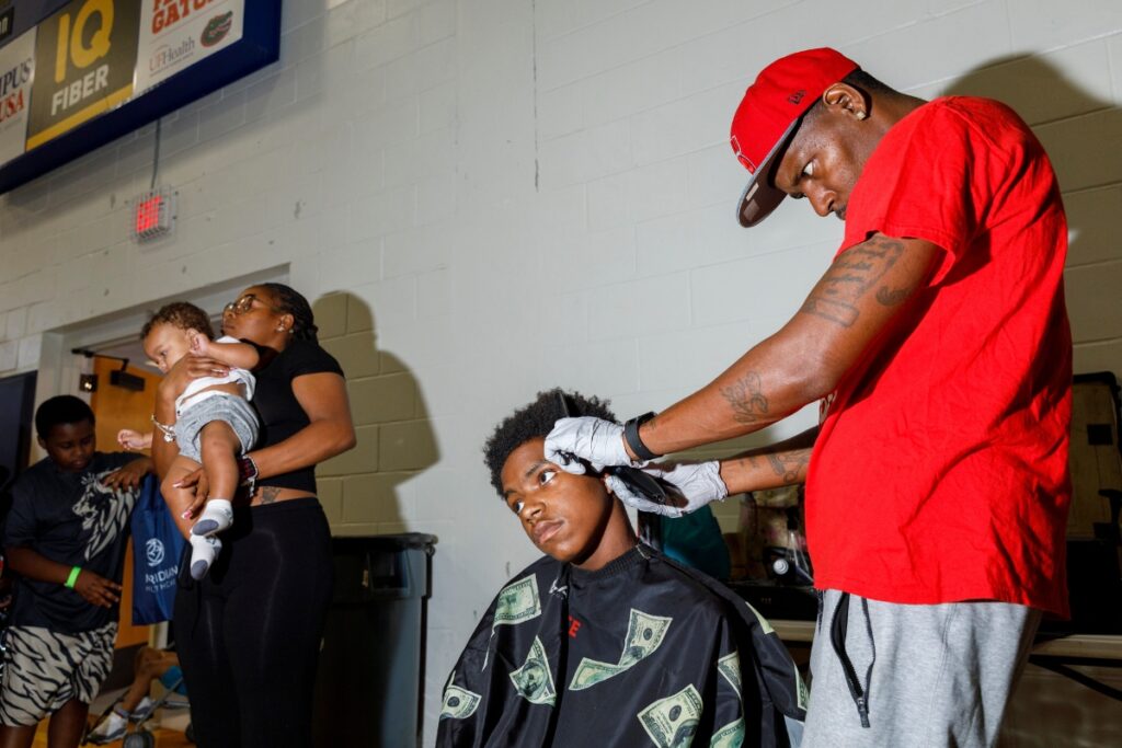 Amp da Barber gives a free haircut to a student during the 27th annual "Back to School" event at Santa Fe College.