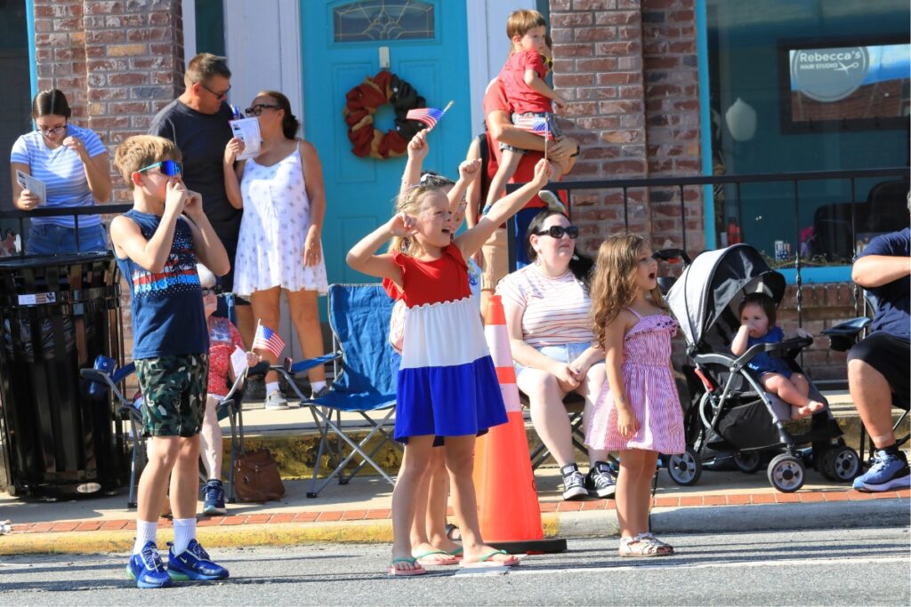 Kids wave and whistle as parade floats come close. 