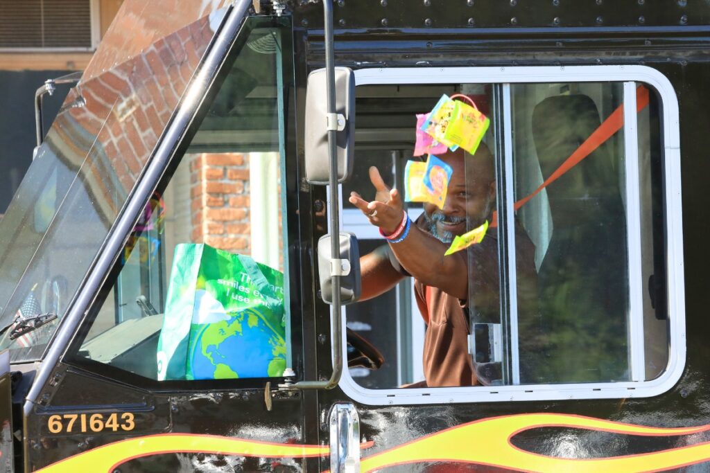 Newberry Commissioner Tony Mazon throws out candy from his UPS vehicle with hot rod flames down the side. 