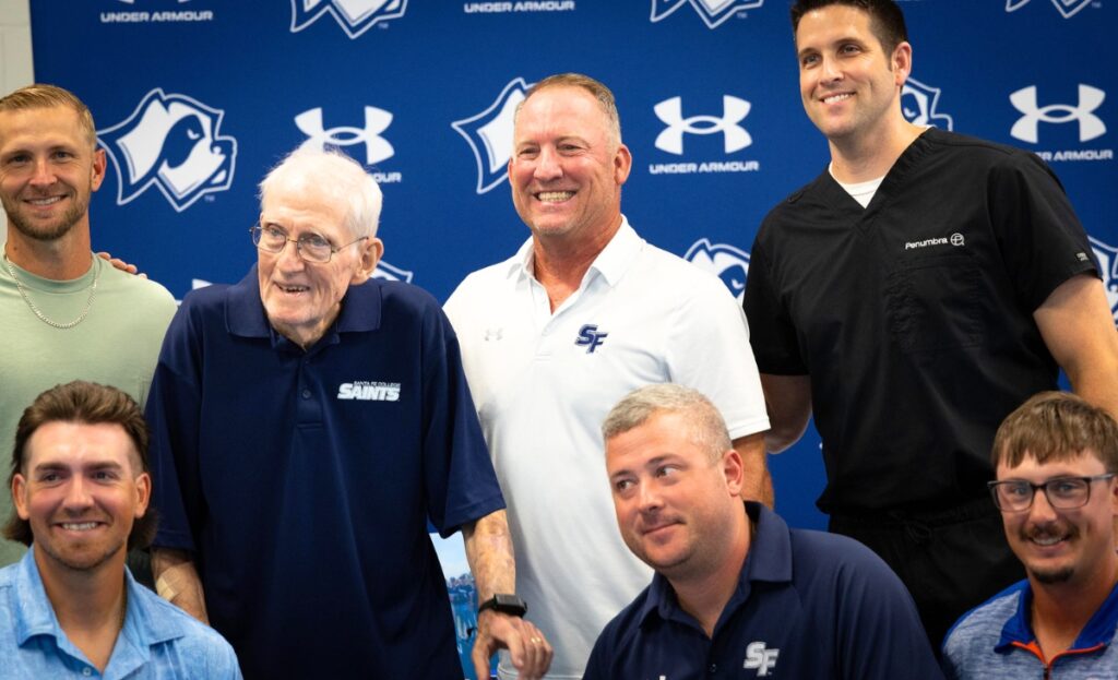 Santa Fe College head baseball coach Johnny Wiggs poses for a photo with former players and coaches during his retirement celebration at the Santa Fe College Gymnasium lobby on Wednesday.