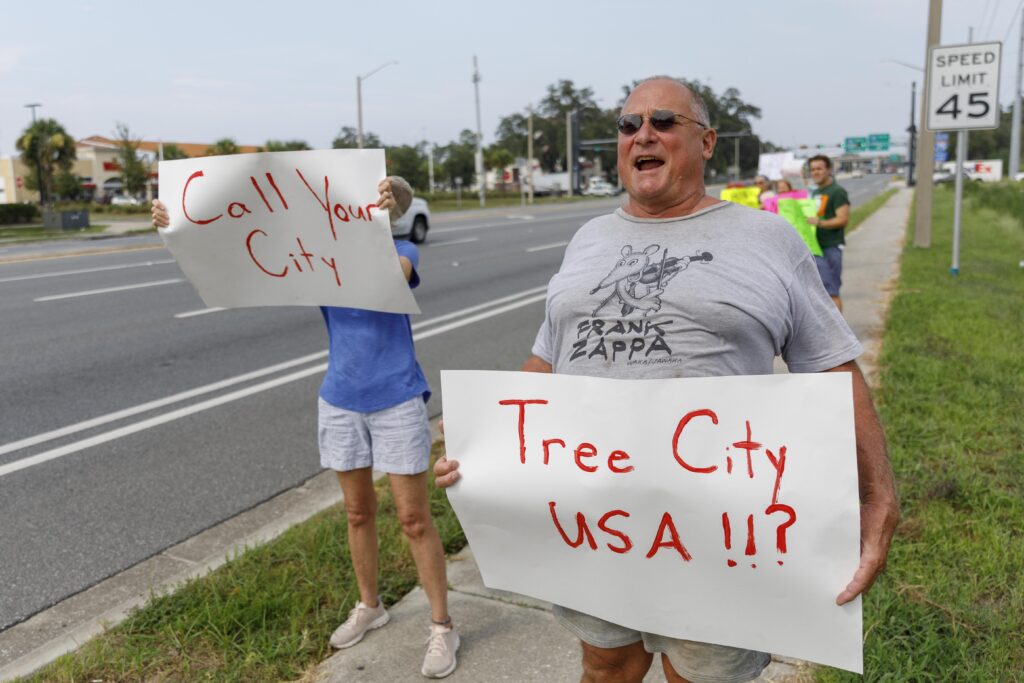 William Toreki protests along Archer Road in Gainesville, Fla., on Wednesday, July 29, 2026, after the clear-cutting of hundreds of trees for the construction of the city's new Fire Station #9. Residents say they support the fire station but object to the removal of the forested buffer that once separated their neighborhood from the roadway.