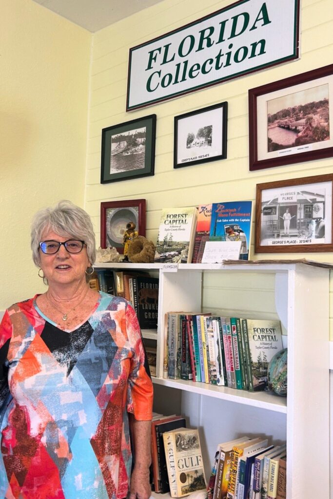 Debra Butler, a member of the Steinhatchee Chamber of Commerce board, at the Little House Library, which she manages. Photo by Ronnie Lovler