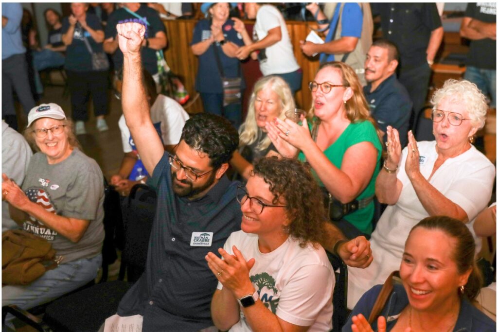 Nathan Crabbe raises his arm after claiming the Gainesville City Commission District 2 seat as election results are announced at Heartwood Soundstage in Gainesville on Tuesday.