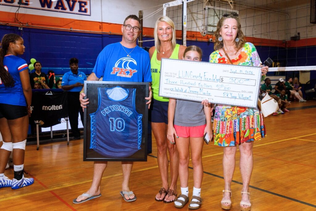 The Martin family holds a check presented by the P.K. Yonge volleyball team in honor of Jeremy Martin, a former PK Yonge alumnus who died from lung cancer. Photo by Walker Smith