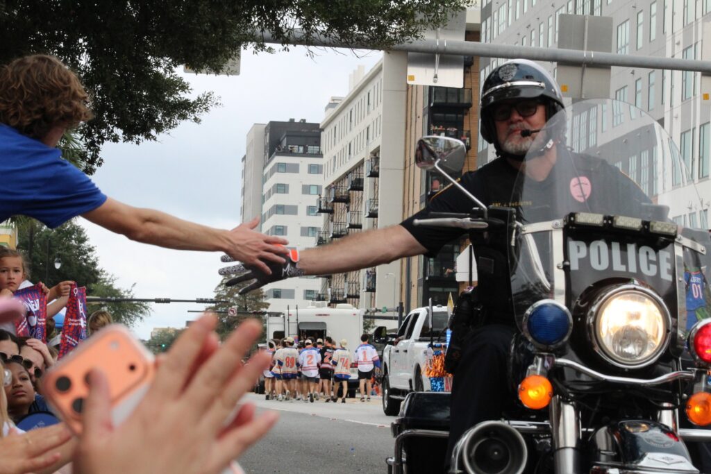 A Gainesville police officer high fives spectators in the UF Homecoming Parade. (Photo by Nick Anschultz)