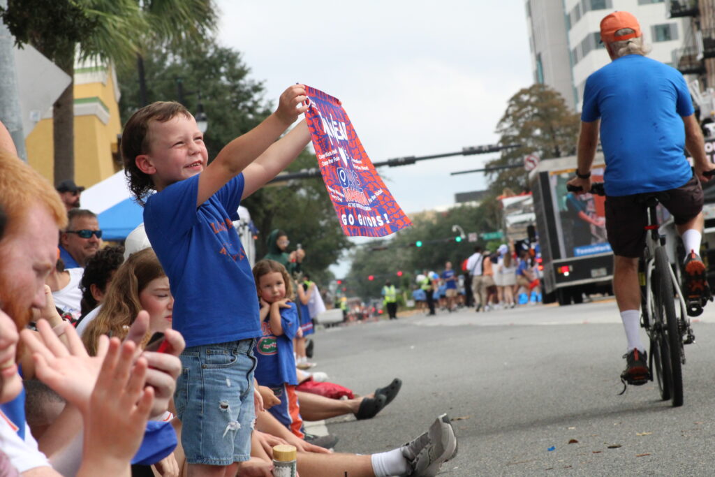 Brett Arnold-Muniz, 6, holds up an orange and blue towel as he watches the UF Homecoming Parade. (Photo by Nick Anschultz)