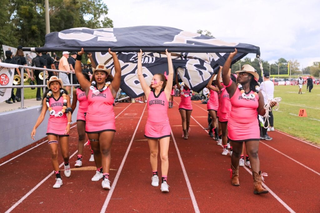 Buchholz High School cheerleaders carry the school banner onto the field before a football game Thursday night. Photo by Walker Smith