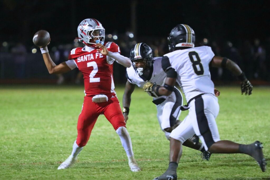 Santa Fe’s Gavin Peterson attempts a pass as the Buchholz defense closes in. Photo by Walker Smith